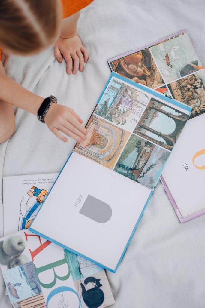 A child reading colorful books, viewed from above, on a cozy setup.